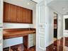 Built-in wood-finish desk with coordinating upper cabinetry, wood-finish flooring, recessed lighting, and panel-style doors