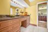 Extended vanity with integrated makeup area, dark stone countertop, and ample storage cabinetry with gold-tone hardware
