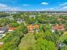 Expansive property with a central residence featuring a barrel tile roof, surrounded by mature trees and lush green landscaping