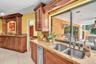 Kitchen featuring wood cabinetry, light-toned granite countertops, a stainless steel double basin sink, and a built-in stainless steel dishwasher