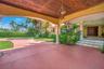 Covered entry with wood-paneled ceiling, decorative chandelier, and stone columns