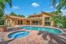 Mediterranean-style architecture featuring a tile roof, stucco exterior, a large in-ground swimming pool, an integrated spa, and an expansive paver pa