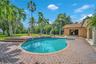 Freeform swimming pool with a textured tile border, surrounded by brick paver decking