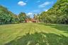 Expansive grassy lawn surrounded by mature trees and lush tropical foliage