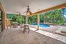 Covered patio with ceiling fans, a built-in outdoor grill, a freeform swimming pool, and extensive brick paver decking
