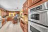 Kitchen featuring wood cabinetry, stainless steel double wall ovens, granite countertops, and tile flooring