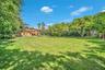 Expansive green lawn with mature trees and a two-story residence featuring a tile roof