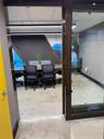 Concrete flooring, contemporary linear lighting fixtures, wood-finish door frames, glass partition, and acoustic paneling