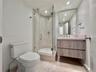 Glass-enclosed shower with a tiled interior, floating vanity with wood-finish cabinetry, and a framed mirror