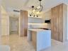 Modern kitchen featuring wood-finish cabinetry, a waterfall island, and recessed lighting
