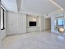 Light-toned tile flooring, built-in light wood-finish cabinetry, and a recessed entertainment area with accent lighting