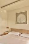 Recessed ceiling panel, fabric upholstered headboard, suspended spherical light fixture, and wood-finish side table with white top