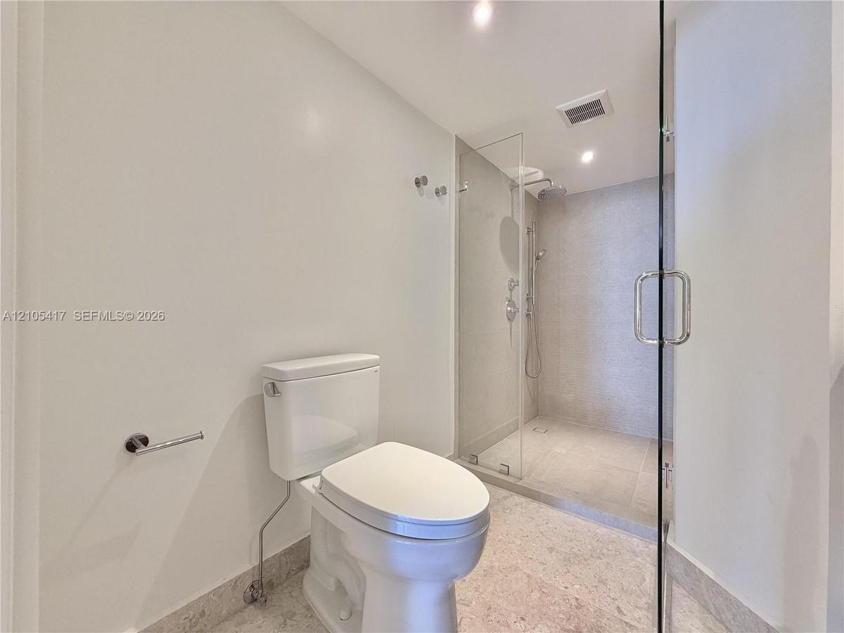 Full glass-enclosed shower with a rainfall showerhead, handheld shower fixture, and polished chrome hardware