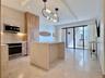 Modern kitchen featuring wood-finish cabinetry, stainless steel appliances, and a waterfall island with integrated seating