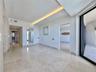 Polished tile flooring throughout, recessed ceiling lighting, a sliding glass door to exterior, and a hallway featuring additional recessed lighting