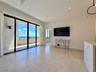 Large-format tile flooring, recessed ceiling lighting, a wall-mounted flat-screen television, a built-in wall niche, and sliding glass balcony doors
