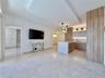 Recessed lighting, wood-finish cabinetry, a central kitchen island, light-toned tile flooring, and a contemporary pendant light fixture