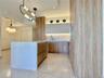 Kitchen featuring wood-finish cabinetry, a large center island with a light-toned countertop, integrated refrigeration, and unique overhead lighting f