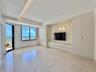 Integrated built-in cabinetry, recessed ceiling lighting, a wall-mounted media console, and a private balcony