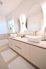 Floating vanity with dual vessel sinks, wall-mounted fixtures, and integrated lighting