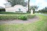 Community entrance sign featuring a decorative arch, textured stucco finish, and lush green landscaping