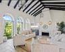 Vaulted ceilings with exposed beams, arched windows, stone tile flooring, and a built-in fireplace
