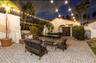 Paved patio featuring a stucco exterior, clay tile roof, and mature palm trees