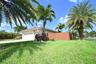 Mediterranean-inspired exterior with a terracotta tile roof, attached garage, and a paver driveway