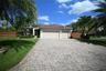 Paved driveway leading to a two-car garage, mature palm trees, and a terracotta tile roof