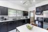 Kitchen featuring black cabinetry, white countertops, stainless steel sink, a stainless steel refrigerator, and a built-in microwave