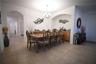 Dining area featuring tile flooring, an arched doorway, and a built-in wet bar with wood-finish cabinetry and a stone countertop