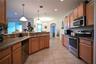 Kitchen featuring wood cabinetry, stainless steel appliances, granite countertops, and tile flooring
