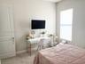 Wall-mounted television, neutral wall color, window with cellular shade, paneled door, and carpeted flooring