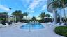 Outdoor swimming pool with integrated steps, surrounded by a paved deck, multiple lounge chairs, and pergolas