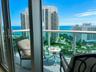 Sliding glass doors opening to a private balcony with glass panel railing and a partial ocean backdrop