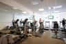 Fitness center with mirrored wall, multiple cardio machines, mounted flat-screen displays, and recessed lighting