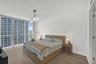 Expansive window wall with city backdrop, wood-finish flooring, and a contemporary ceiling fixture