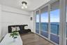 Expansive sliding glass doors, water scenery, balcony with metal railing, wood-finish flooring, and a contemporary semi-flush mount light fixture