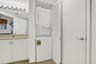 Built-in stacked washer and dryer, vanity with a rectangular sink, wall-mounted light fixture, and white cabinet storage