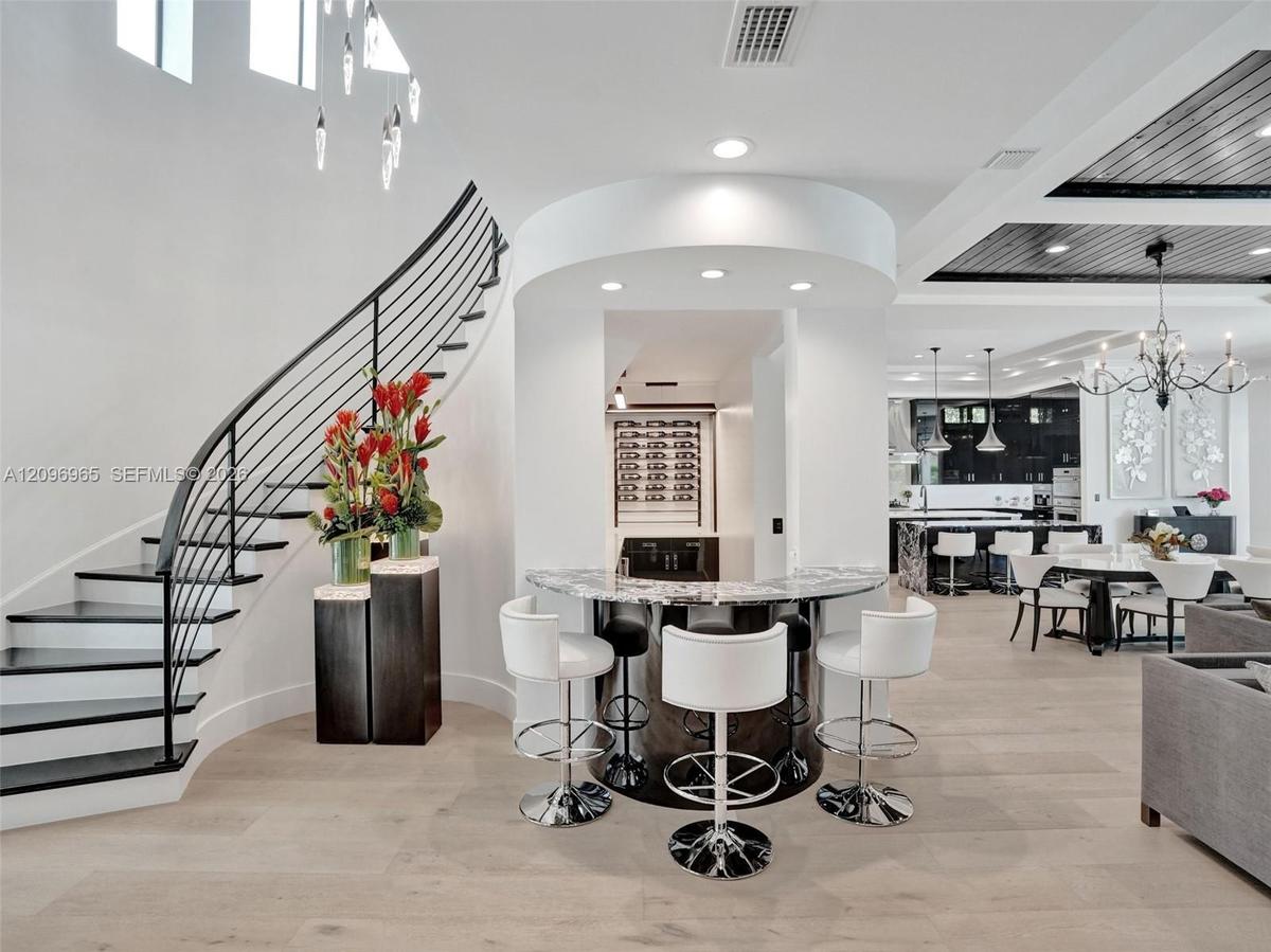 Curved staircase featuring a metal railing, wood-finish flooring, textured metallic wall accent, recessed ceiling lighting, and a built-in circular ba