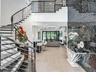 Curved staircase with black metal railings, light wood-finish flooring, and a textured black accent wall