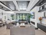 Curved staircase with black metal railing, built-in wet bar featuring stone-surface countertop, recessed lighting, plank-style flooring, and coffered 