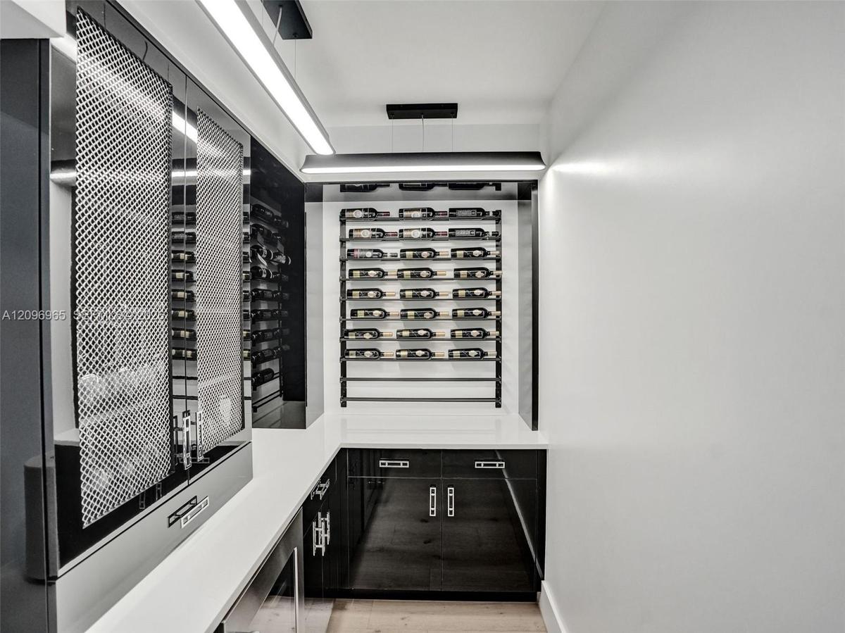 Double-height foyer featuring a prominent floor-to-ceiling textured black tile accent wall, wood-finish flooring, and a metal horizontal-bar staircase