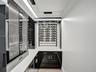 Double-height foyer featuring a prominent floor-to-ceiling textured black tile accent wall, wood-finish flooring, and a metal horizontal-bar staircase