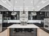 Custom wine cellar featuring horizontal metal racking, high-gloss cabinetry, linear pendant lighting, and a white countertop