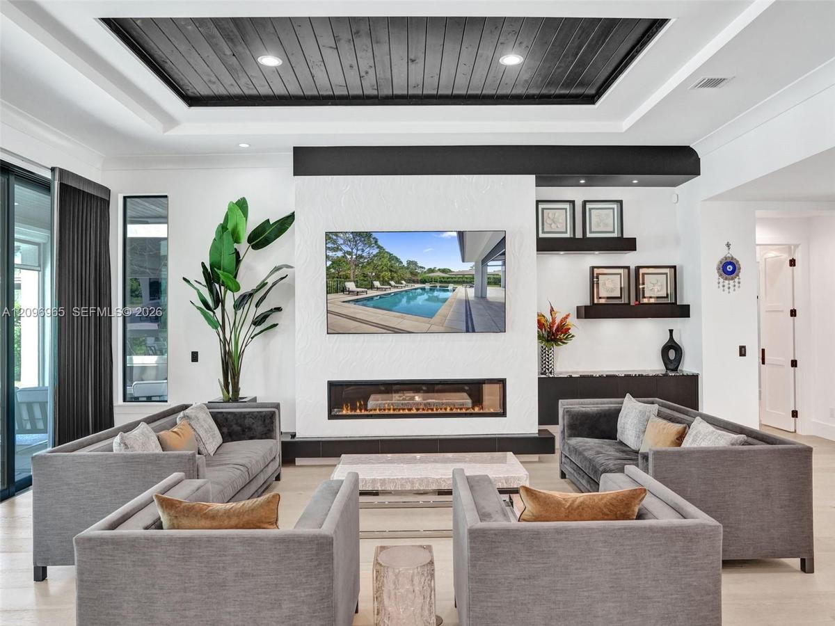 Coffered ceiling featuring dark wood-finish planking, linear fireplace with a textured surround, recessed lighting, multi-panel glass sliding doors, a