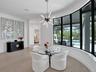 Modern kitchen featuring high-gloss black cabinetry, dual islands with contrasting surfaces, wood-finish flooring, recessed tray ceiling lighting, and