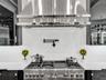 Custom wine display featuring horizontal metal racking, high-gloss black cabinetry, white countertops, and integrated linear lighting