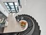 Kitchen featuring a central island with a solid surface countertop, high-gloss cabinetry, recessed ceiling tray detailing, wood-finish flooring, and m