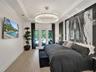 Kitchen featuring high-gloss cabinetry, stone-surface waterfall island with seating, wood-finish flooring, stainless steel appliances, and a recessed 